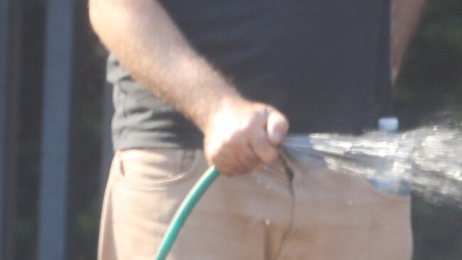 A Sydney gardener using a hose with no trigger nozzle when level 1 water restrictions were in place. Picture: John Grainger.