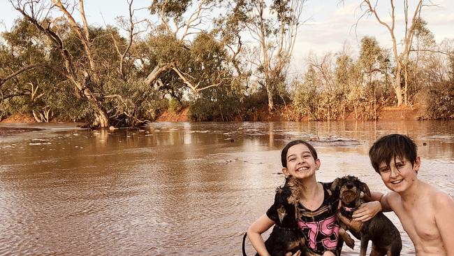 Jake and Zahli Finch with their pups Bailey and Hazel playing in Stephens Creek, Broken Hill. Picture: Kelly Finch