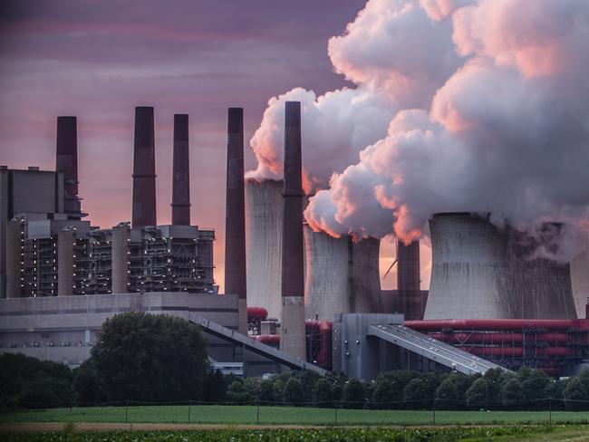 Industry in dramatic red sunset light. Chimneys and cooling tower of a coal fired power station.