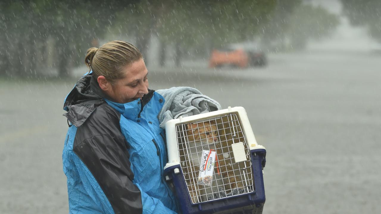 Sunday February 2. Heavy rain lashes Townsville causing flash flooding. Jo Martin carries her cat Kramer in Carmody Street, Rosslea. Picture: Evan Morgan