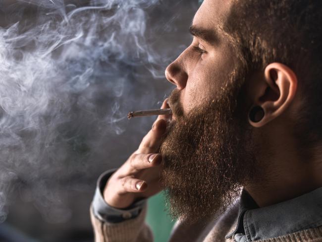 Close up of hipster man smoking weed cigarette.