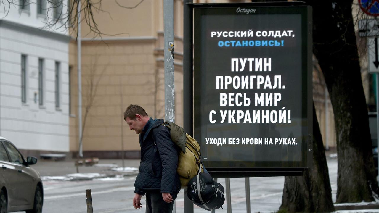 A man walks past a board with a message reading "Putin is lost. The entire world is with Ukraine!" set in Ukrainian capital of Kyiv. Picture: Sergei Supinsky / AFP