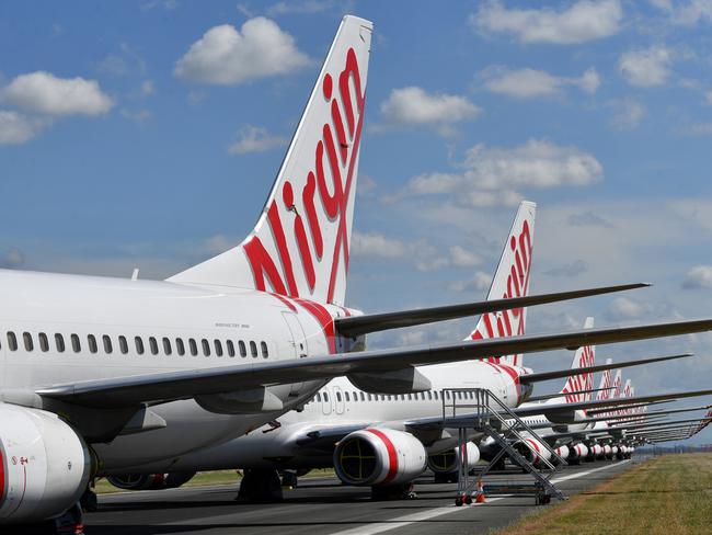 Grounded Virgin Australia aircraft are seen parked at Brisbane Airport in Brisbane, Tuesday, April 7, 2020. Brisbane Airport Corporation (BAC) is working with airlines by accommodating up to 100 grounded aircraft free of charge in response to government-mandated travel restrictions that have grounded a significant proportion of Australia's airline fleet because of the Coronavirus (COVID-19). (AAP Image/Darren England) NO ARCHIVING