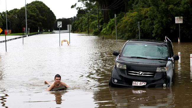 Milperra local resident Isaac Collier (17) on his boogie board next to an abandoned car caught in the flood waters on the flooded Georges River, southwestern Sydney. Picture: Jane Dempster/The Australian.