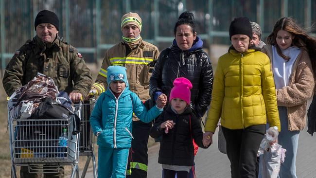 A Polish serviceman, left, helps Ukrainian refugees cross the Ukrainian border on Sunday. Picture: AFP