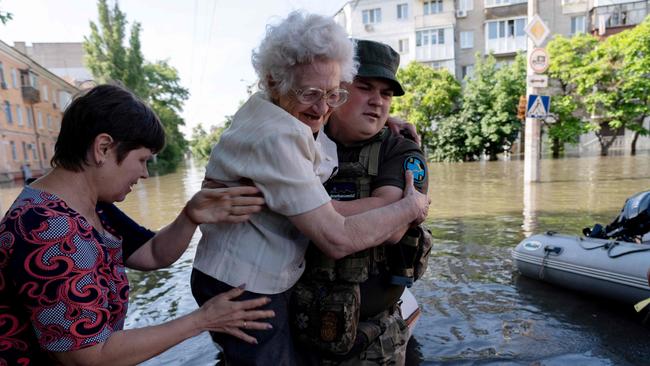 A Ukrainian serviceman help local residents during an evacuation from the flooded in Kherson, following the attack on the Kakhovka hydroelectric power plant dam. (Photo: Aleksey Filippov/AFP.)