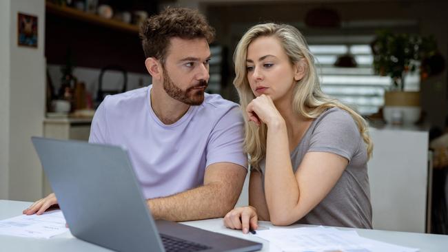 Young couple checking their home finances and looking worried while looking at their bank statements online; money budgeting stress banking generic