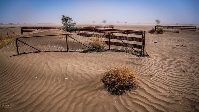 A fence and gate are covered in windblown soil as a dust storm blows though a drought-affected property located on the Moree Plains and on the outskirts of the northwestern New South Wales town of Collarenebri.