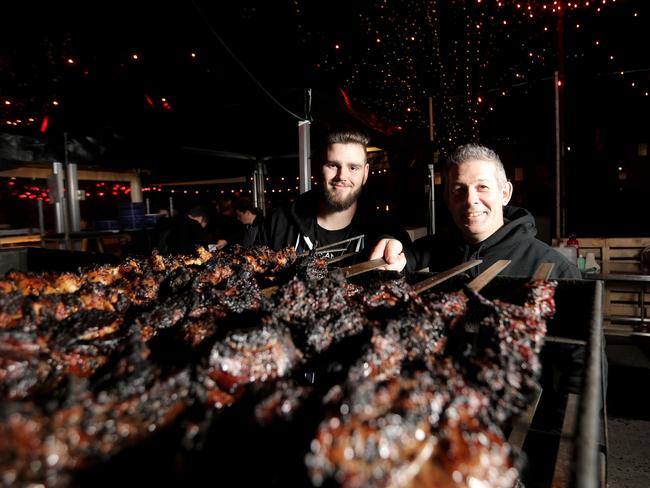 Heavy Metal Kitchen chefs Luke Roe and Stephen Lunn turning meat roasted over an open pit fire. Picture: LUKE BOWDEN