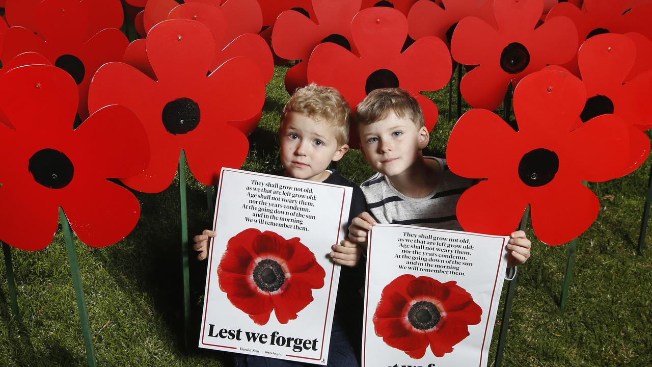 ANZAC giant poppies. Felix 4 and Oscar 6 hold the Herald Sun Poppy Poster with the poppies they made with their parents Mark and Sarah Algie in the garage for family and friends. Picture: David Caird