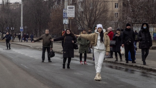 Ukrainians with no transport trying to wave down buses and other motorists for a ride out of cities. Picture: Chris McGrath/Getty Images
