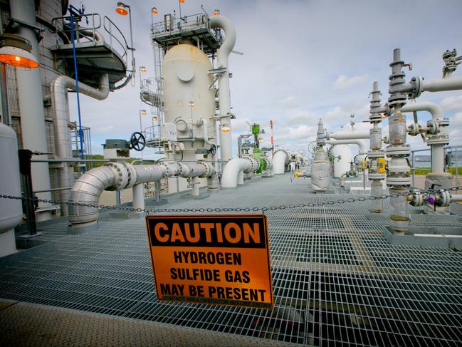 A sign warning of the presence of hydrogen sulfide gas hangs across a walkway at the Queensland Curtis Liquefied Natural Gas (QCLNG) project site, operated by QGC Pty, a unit of Royal Dutch Shell Plc, in Gladstone, Australia, on Wednesday, June 15, 2016. Gas from more than 2,500 wells travels hundreds of miles by pipeline to the project, where it's chilled and pumped into 10-story-high tanks before being loaded onto massive ships. Photographer: Patrick Hamilton/Bloomberg