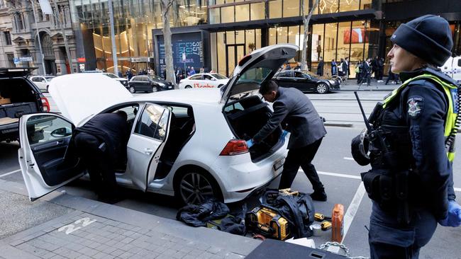 Police go through the white hatchback on Collins St on Wednesday. Picture: David Geraghty / NewsWire