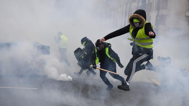 Yellow Vest (Gilets Jaunes) protesters run away from tear gas during long-running anti-government demonstrations in 2019.