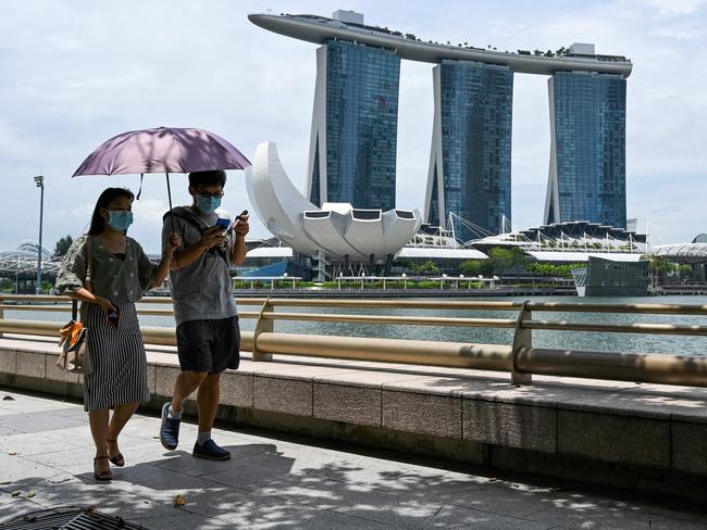 A couple wearing face masks walks along the Marina Bay in Singapore. Picture: AFP