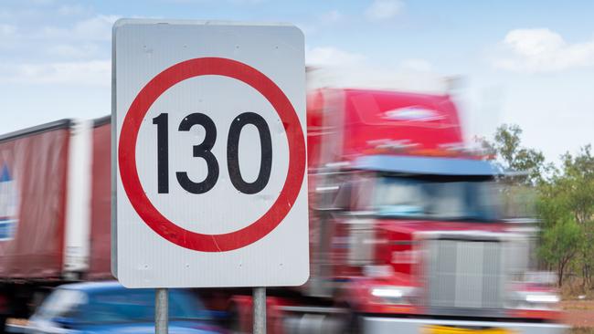 Cars and road trains pass a road sign announcing a new speed limit of 130kmh on the Stuart Highway. Picture: Che Chorley