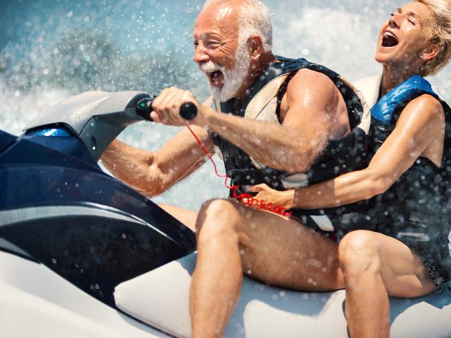 Retirement, travel generic: Closeup side view of a senior couple riding a jet ski on a sunny summer day at open sea.