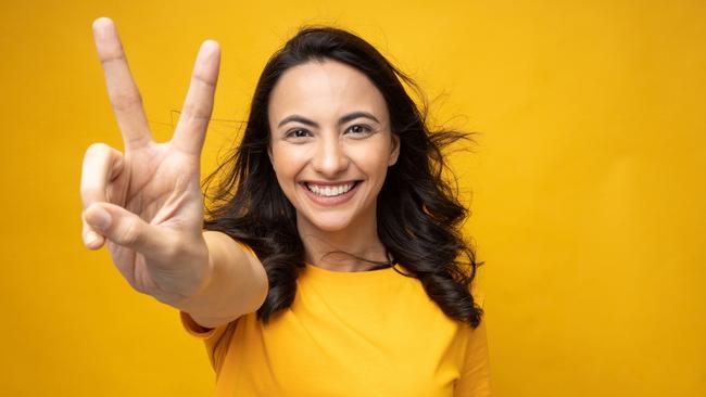 Portrait of young woman wear trendy smart casual outfit isolated on yellow background; two fingers double-digit victory sign generic