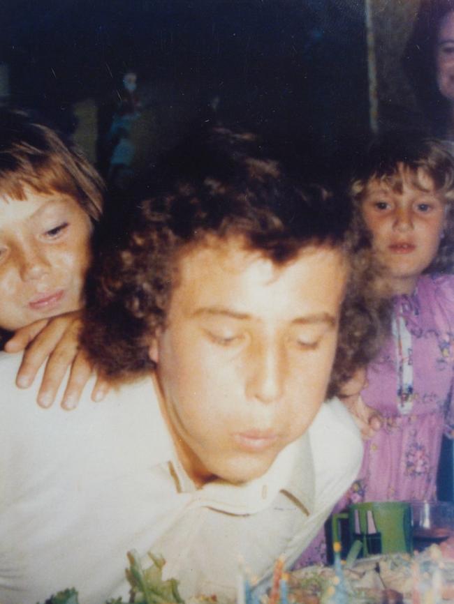 James Dack blowing out birthday candles with his siblings in rear. Picture: Supplied