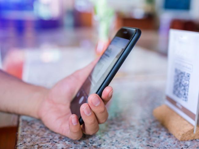 Closeup of a hand holding phone and scanning qr code. Man hand paying with qr code. Customer hand making payment through smart phone and scan code. Selective focus