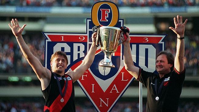 Kevin Sheedy (right) holds the 1993 premiership cup aloft with former skipper and now Essendon interim coach Mark Thompson. 