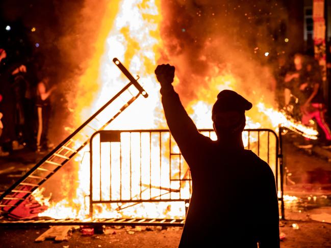 TOPSHOT - A protester raises a fist near a fire during a demonstration outside the White House over the death of George Floyd at the hands of Minneapolis Police in Washington, DC, on May 31, 2020. - Thousands of National Guard troops patrolled major US cities after five consecutive nights of protests over racism and police brutality that boiled over into arson and looting, sending shock waves through the country. The death Monday of an unarmed black man, George Floyd, at the hands of police in Minneapolis ignited this latest wave of outrage in the US over law enforcement's repeated use of lethal force against African Americans -- this one like others before captured on cellphone video. (Photo by Samuel Corum / AFP)