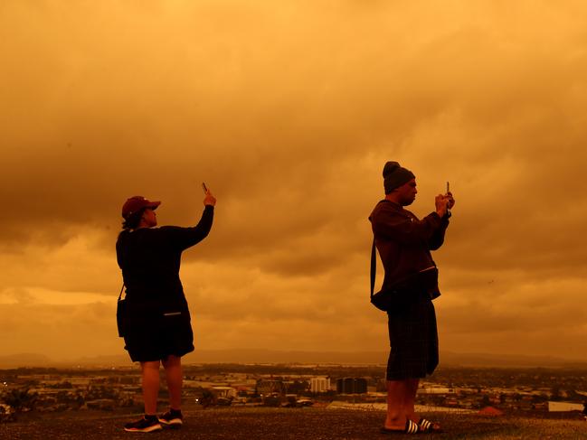 People at Totara Park in Manukau photograph the tobacco coloured skies over Auckland, New Zealand. Picture: Phil Walter/Getty