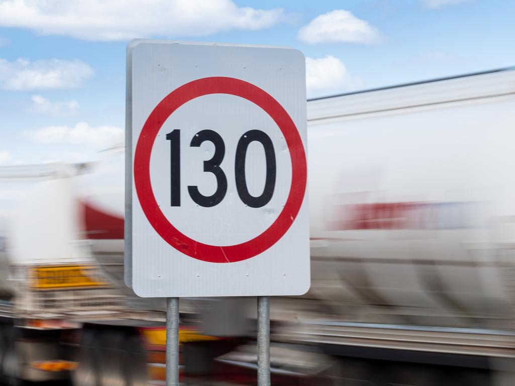 Cars and road trains pass a road sign announcing a new speed limit of 130kmh on the Stuart Highway.Picture: Che Chorley