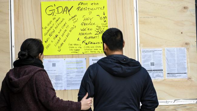 Residents read billboards posted at the building’s entrance. Picture: Darren Leigh Roberts