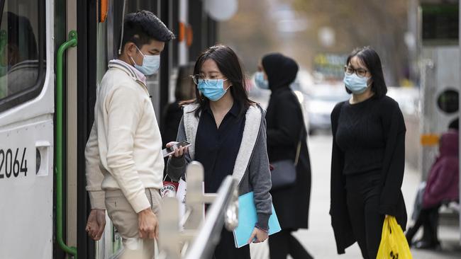 People wearing face masks boarding and disembarking a tram in Melbourne on Thursday. Picture: Getty Images