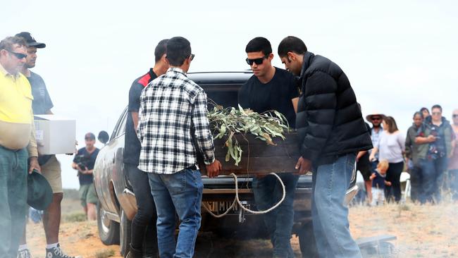 The remains of Mungo man is unloaded from the hearse at the ceremony in Mungo National park. Picture: Aaron Francis