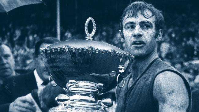 Footballer Bob Shearman holding Thomas Seymour Hill trophy after Sturt won five premierships in a row – Sturt vs. Glenelg Grand Final match 1970