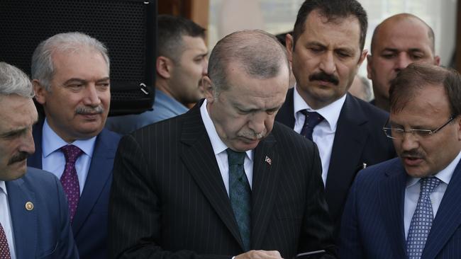 Turkey's President Recep Tayyip Erdogan, centre, looks at his phone during a ceremony in Istanbul. Picture: AP