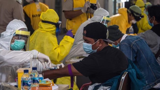 Indonesian officials conduct health screening on 156 migrant workers who arrived from Malaysia at Surabaya airport in Indonesia's East Java. Picture: AFP