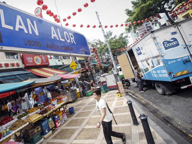 A tourist walks past Malaysia's famous eatery street, Jalan Alor, a popular tourist spot in Kuala Lumpur, Malaysia on Friday, Sept. 25, 2015. The U.S. Embassy issued an advisory Thursday saying it has credible threat information and urged its citizens to avoid Alor Street, located in a shopping belt in the city center, and its immediate surrounding areas. (AP Photo/Joshua Paul)