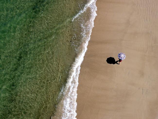 A lone woman walks along Brighton Beach. Picture: Kelly Barnes