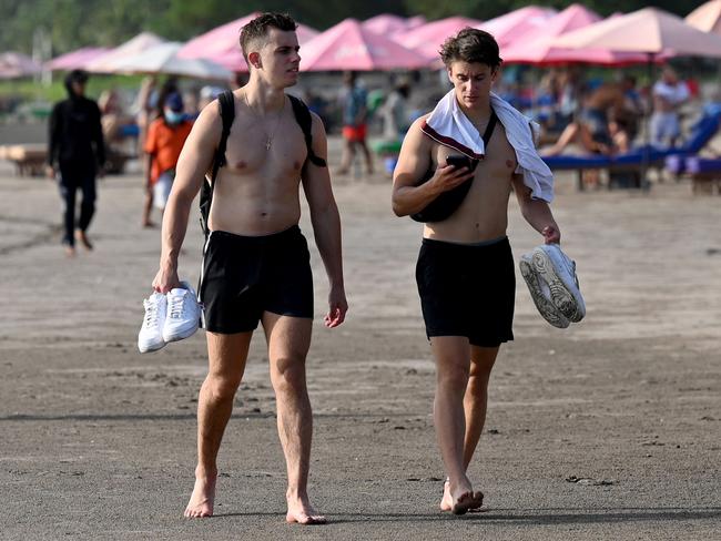 Foreign tourists walk on a beach in Seminyak, Badung regency on Indonesia resort island of Bali, on December 7, 2022. (Photo by SONNY TUMBELAKA / AFP)