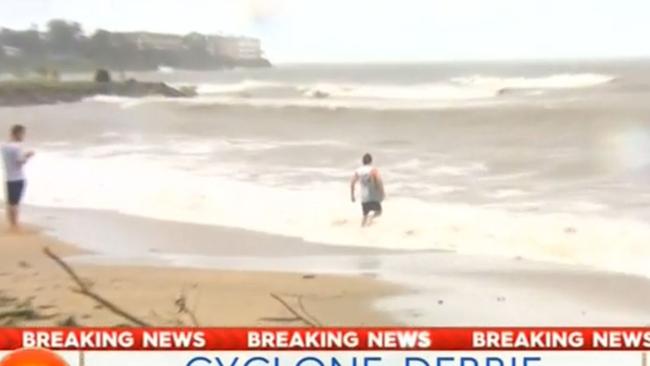 The man is watched by a mate as he carries his boogie board into the surf. Picture: Channel 9