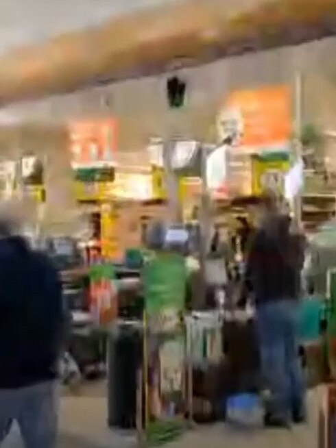 This shopper is seen scanning his items at the self-serve checkout, despite the fire engulfing the shop.