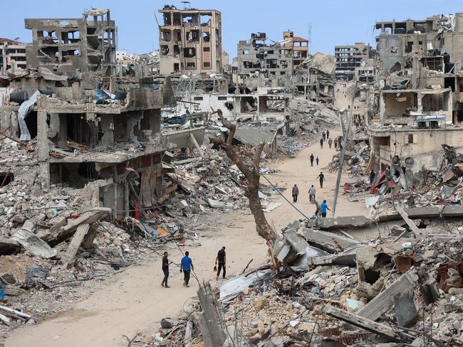 Palestinians walk on a dirt road lined with rubble from destroyed buildings in the Shujaiya neighbourhood of Gaza City. Picture: Omar Al-Qattaa / AFP