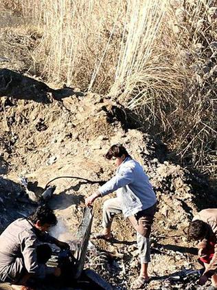 IS group's fighters inspect the wreckage of the warplane.
