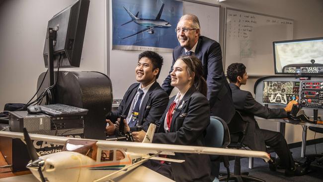 Students Matthew Saengrat and Grace Alberti from Brisbane's Aviation High practice flying on simulators while principal David Munn watches on. Photo: Glenn Hunt / The Australian