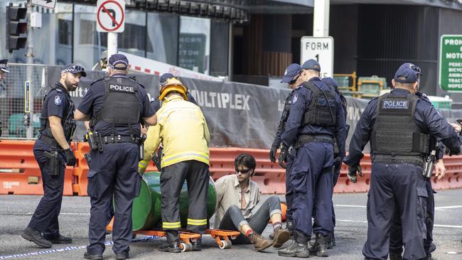 An activist from Extinction Rebellion, with his arm in a barrel of cement, participating in a protest on George Street, Brisbane on Tuesday. Picture: AAP Image/Glenn Hunt