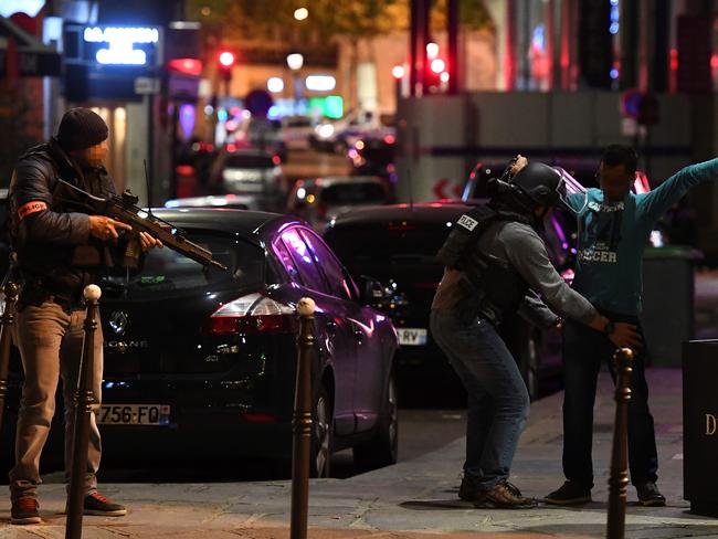 Police officers frisk a man on the Champs Elysees in Paris after the deadly shooting.