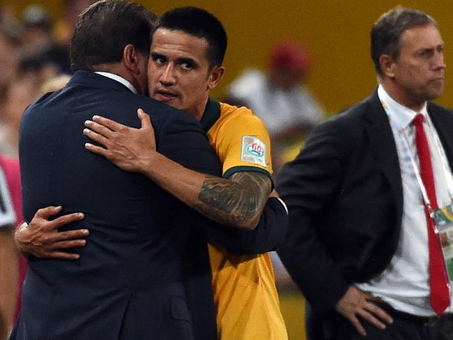 Australia's Tim Cahill (C) hugs his team coach Ange Postecoglou (L) as China's coach Alain Perrin (R) looks after the AFC Asian Cup quarter-final football match between Australia and China in Brisbane on January 22, 2015. AFP PHOTO / Saeed KHAN --IMAGE RESTRICTED TO EDITORIAL USE - STRICTLY NO COMMERCIAL USE--