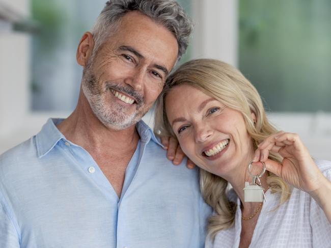 Mature couple with the key to their new house. They are happy and smiling. The kitchen can be seen in the background. Home housing unlocking equity generic