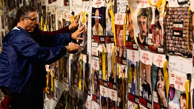 A protester adds a portrait on the wall during a rally for supporters and relatives of Israeli hostages held in Gaza since the October 7 attack in Tel Aviv.