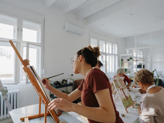 Photo of a young female teacher explaining how to paint to a group of senior students; holding a class in her art studio and teaching basic painting techniques. Photo: iStock