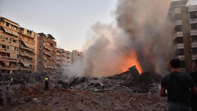 People watch as a blaze rages amid the smouldering rubble of a building destroyed in an Israeli air strike in Beirut's southern suburbs on September 27, 2024. (Photo by Fadel ITANI / AFP)