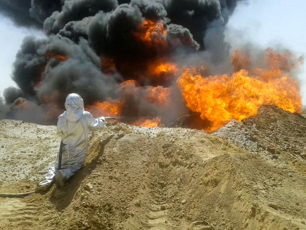 Civil defence first responders work to extinguish a fire on an oil pipeline in Furqlus, central-west Syria. Picture: SANA/AFP